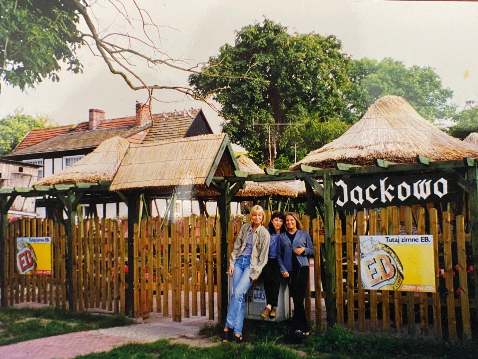 Jackowo w 2000 roku: strzechy, drewniany płot i szyld nad wejściem