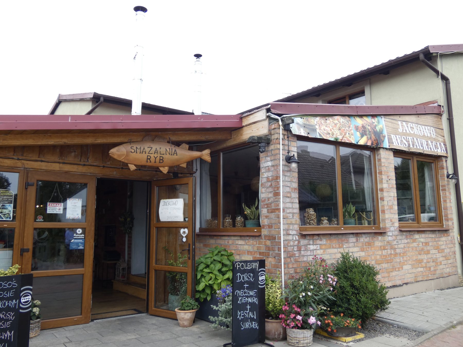 Wejście do restauracji i smażalni ryb Jackowo, szyldy nad drzwiami