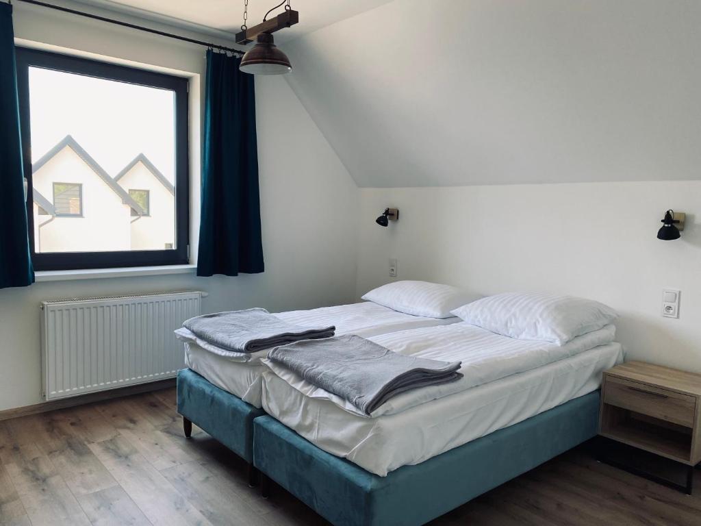Sypialnia na poddaszu apartamentu dwupoziomowego, skos i okno na dachy sąsiednich domów